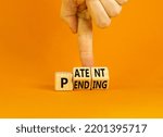 Small photo of Patent pending symbol. Concept words Patent pending on wooden cubes. Businessman hand. Beautiful orange table orange background. Business and patent pending concept. Copy space.