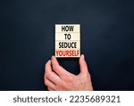 Small photo of How to seduce yourself symbol. Concept word How to seduce yourself on wooden blocks. Businessman hand. Beautiful black table black background. Business and how to seduce yourself concept. Copy space.