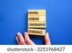 Small photo of MACD symbol. Concept words MACD moving average convergence divergence on wooden block on beautiful blue background. Business MACD moving average convergence divergence concept. Copy space.