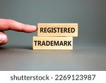 Small photo of Registered trademark symbol. Concept word Registered trademark wooden blocks. Beautiful grey table grey background. Businessman hand. Business and registered trademark concept. Copy space.