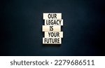 Small photo of Legacy and future symbol. Concept words Our legacy is your future on wooden blocks. Beautiful black table black background. Business legacy and future concept. Copy space.