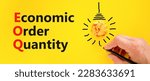 Small photo of EOQ economic order quantity symbol. Concept words EOQ economic order quantity on paper on beautiful yellow background. Orange light bulb icon. Business EOQ economic order quantity concept. Copy space.