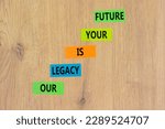 Small photo of Legacy and future symbol. Concept words Our legacy is your future on colored paper. Beautiful wooden table wooden background. Business legacy and future concept. Copy space.