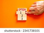 Small photo of Time to option 1 symbol. Concept word Option 1 2 3 on wooden block. Businessman hand. Beautiful orange table orange background. Business planning and time to option 1 concept. Copy space.
