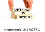 Small photo of Anything is possible symbol. Concept words Anything is possible on beautiful wooden blocks. Beautiful white table white background. Businessman hand. Business anything possible concept. Copy space.