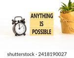 Small photo of Anything is possible symbol. Concept words Anything is possible on beautiful wooden blocks. Beautiful white table white background. Black alarm clock. Business anything possible concept. Copy space.