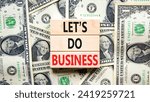 Small photo of let is do business symbol. Concept words let is do business on beautiful wooden blocks. Dollar bills. Beautiful dollar bills background. let is do business concept. Copy space.