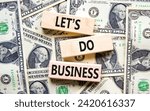 Small photo of let is do business symbol. Concept words let is do business on beautiful wooden blocks. Dollar bills. Beautiful dollar bills background. let is do business concept. Copy space.