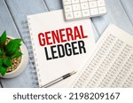 Small photo of GENERAL LEDGER text written on white notebook with calculator and pen