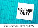Small photo of fiduciary duty word on torn paper with blue wooden background