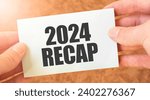 Small photo of 2024 RECAP word inscription on white card paper sheet in hands of a businessman. recap concept. red and white paper