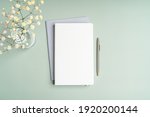 Top view blank paper Notebook, flowers, water with lemon and pen. Desktop mock up, Flat lay of green working table background with office equipment, mockup greeting card