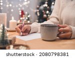 Goals plans make to do and wish list for new year christmas concept writing in notebook. Woman hand holding pen on notepad and coffee cup at home on winter holidays xmas.