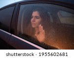 Small photo of Close-up young woman inside car looking through window place hand on glass with melancholy face.