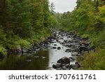 Rocky section of Peshekee River bordered by trees in Upper Peninsula of Michigan