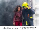 Firefighter emergency rescue help young woman from dangerous smoke and burning building accident. - Safety and rescue operation comcept