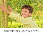 Small photo of A baby boy trying to climb on a tree. Moving towards sauces concept of climbing on tree. Learning climbing process. Pakistani kid practicing to climb on a tree. Asian kid climbing on tree.