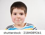 Small photo of A preschool child of 4 years old with red cheeks looks into the camera, face close-up. Diathesis in children or redness of the cheeks after cold and frost