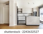 Small photo of Front of a recently installed modern style kitchen with handleless cabinets, marble island and stoneware floors combined with laminated flooring with access to a glazed terrace