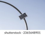 Small photo of A photoelectric cell charging device on a curved metal pole
