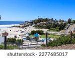 gorgeous shot of the blue ocean water, lush green palm trees and beach houses with people walking along the beach at Moonlight State Beach in Encinitas California USA