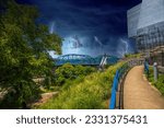 a gorgeous summer landscape along a footpath with a blue handrail surrounded by lush green trees and a bridge at Hunter Museum of American Art in Chattanooga Tennessee USA