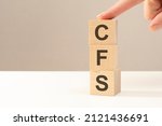 Small photo of the hand puts a wooden cube with the letter CFS - short for Consolidated Financial Statement. business concept. space for text in left. front view