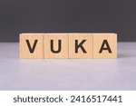 Small photo of blocks forming the word VUKA - concept represents Volatility Uncertainty Complexity Ambiguity. concept strategic planning, leadership, problem-solving and unpredictable conditions.