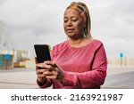 Mature african woman using mobile phone after sport workout in the city