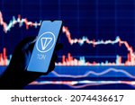 Small photo of Kazan, Russia - Nov 14, 2021: The Open Network is a blockchain-based decentralized computer network technology. A smartphone with the TON Coin logo in hand on stock chart background.