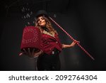Small photo of Female magician makes with soap bubbles show, an illusionist in theatrical clothes, on black background. Woman actress in stage costume. Concept of theatrical performance and fun show. Copy space