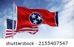 The Tennessee state flag waving along with the national flag of the United States of America. Tennessee is a state in the Southeastern region of the United States