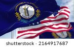 Small photo of The Kentucky state flag waving along with the national flag of the United States of America. In the background there is a clear sky. Kentucky is a state in the Southeastern region of the United States