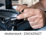 Small photo of Close-up of male hand operating the carriage return lever at a vintage black typewriter.