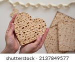 Small photo of Woman's hand holds Matzah shape of heart. Traditional of Holiday on Passover. Home symbol of lovely family. top view, layout. love and care. Jewish pesach. Feeling in love and blissful life