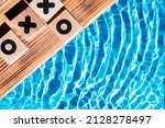 Small photo of Wood sand board coastal with timbered dibs. Blue tide flowing transparent reflect wave water surface ocean. Rivalry playing, cubes noughts, crosses, tick tack toe game. Flat lay. Right place for text.
