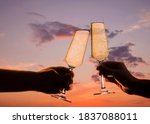 man and woman clink glasses with champagne at sunset