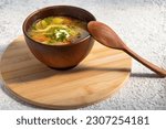 Small photo of Mushroom soup in clay bowl.. Rustic style. Portion of fresh soup in tureen. Wooden spoon. On bamboo stand .