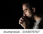 Small photo of The man folding his hands in prayer to god on a black background. prayer to God for happiness and a better life. Repent of your sins. Unity with God