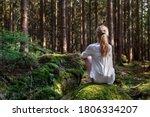 Woman sitting in green forest enjoys the silence and beauty of nature.
