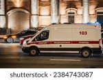 Small photo of Russia, Moscow, 02 nov 2023. White state ambulance van fast moving on night city street. Russian ambulance emergency car in the city. Motion blur