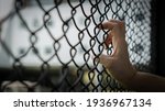 Small photo of Slavery trade and trafficking victim concept of woman prisoner in jail being tortured, punished or abused in violation with hand holding cage wire mesh