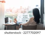 Small photo of Work-Life balance, life quality, work and travel concept with business woman relaxing sitting in rest, take it easy in modern hotel guest room or luxury home living room with notebook and city view