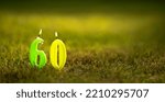 Small photo of Burning candles in the form of the number 60 on a green background. Congratulations on the sixtieth anniversary. A postcard for the 60th anniversary.