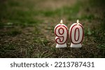 Small photo of Congratulations on your ninetieth birthday. The 90th anniversary. Lighting candles stand on the ground in the form of numbers 90.