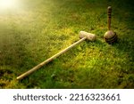 Small photo of A wooden stick with a ball for playing croquet of the last century. Antique croquet set on the green grass in the park.