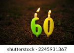 Small photo of Burning candles in the form of numbers sixty. 60 years of candles stuck in the ground.Congratulations on the sixtieth anniversary. Background for congratulations with candles for the anniversary.