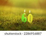 Small photo of Photo of the background to the congratulations on the sixtieth anniversary. Candles in the form of the number 60 are stuck in the grass.