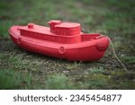 A red plastic children's boat is standing on dry land. Shallowing of the riverbed.The end of shipping.Drought.
