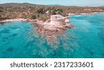Small photo of Aerial view with the drone of the Torre del Lazzaretto in Alghero, surrounded by crystalline blue water and immersed in the suggestive cliffs
